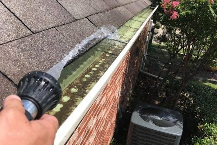 Gutters being rinsed out by a gutter cleaner